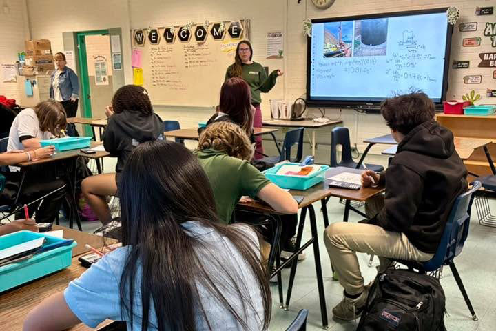A woman talks to a class of middle school students