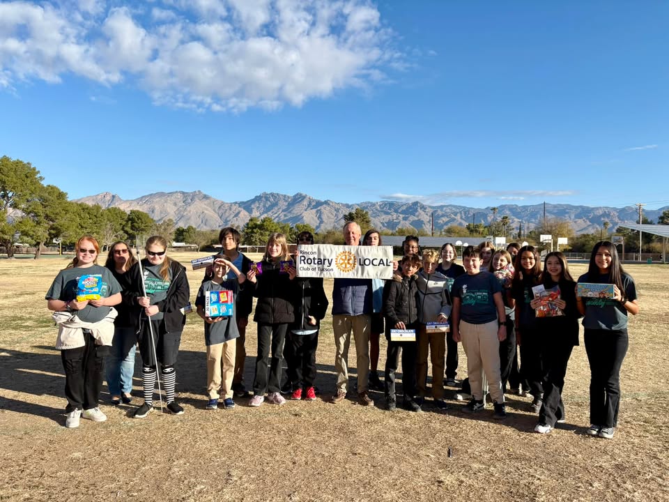 Students stand out in a field in front of mountains