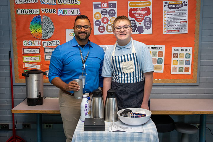 A man and a teen boy smile as they get ready to serve coffee