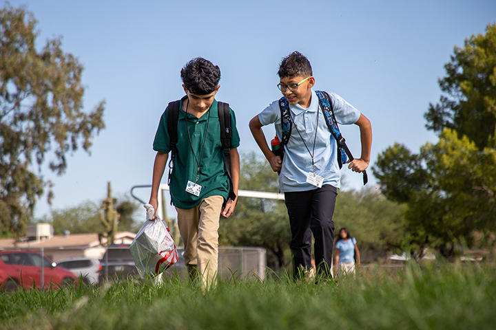 Two boys walk through grass