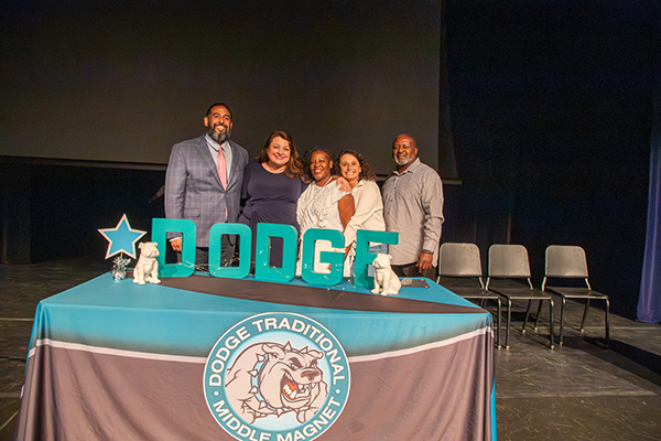 School administrators smile behind the table with turquoise letters spelling Dodge