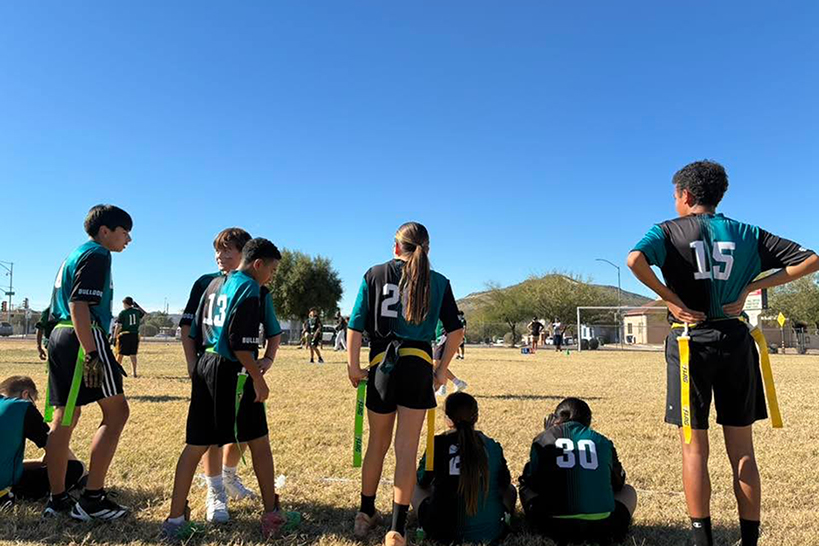 The flag football team stands on the sidelines