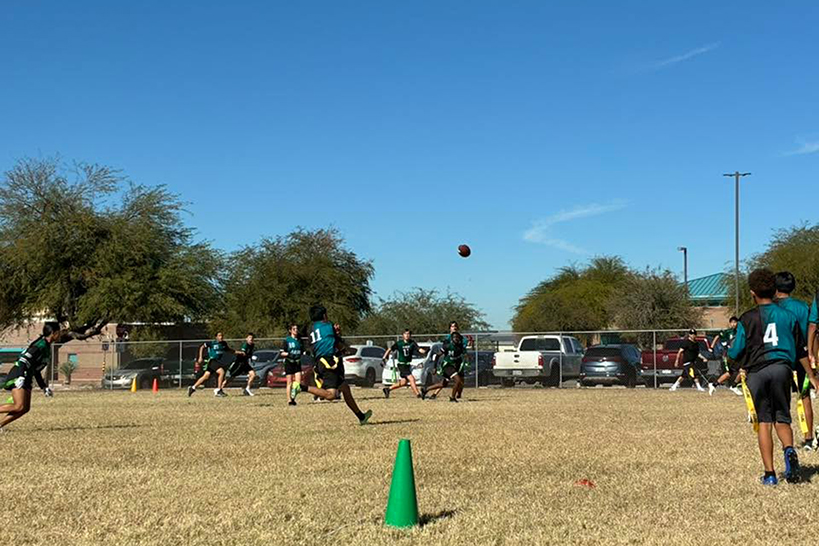 The flag football team runs down the field chasing the ball
