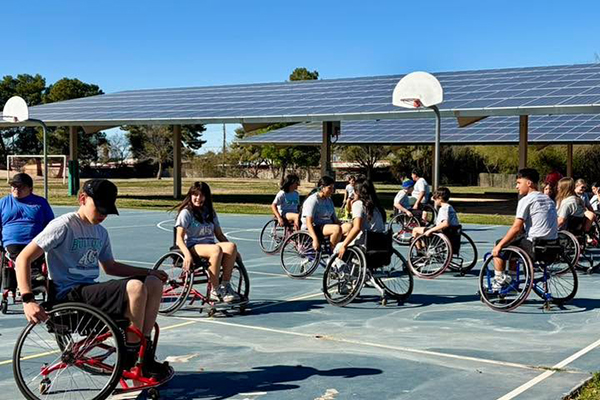 Students move around the basketball court in wheelchairs