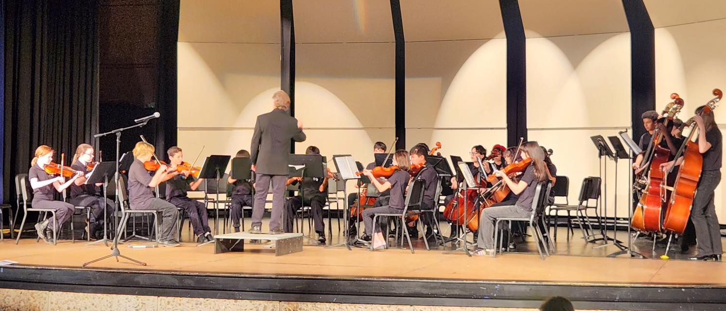 A conductor conducts a middle school orchestra group