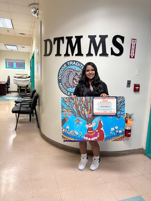 A girl holds up her winning artwork