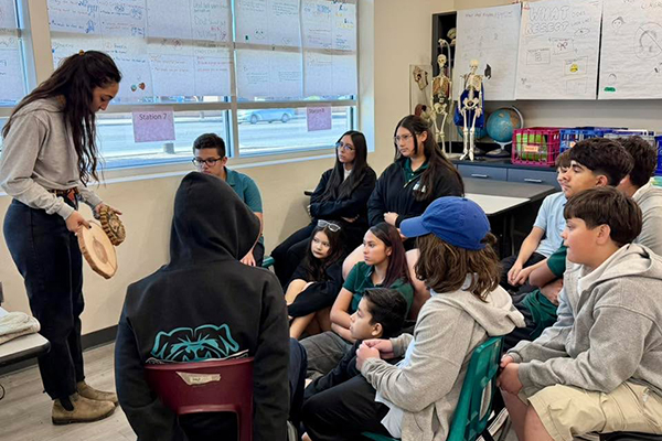 A woman shows students the inside rings of a tree vs a saguaro
