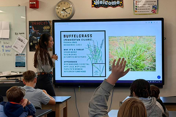 A woman talks to students about the threats of buffelgrass