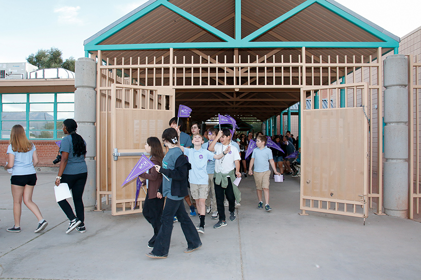 Students walk out of the school waving purple Ruby Bridges pennants