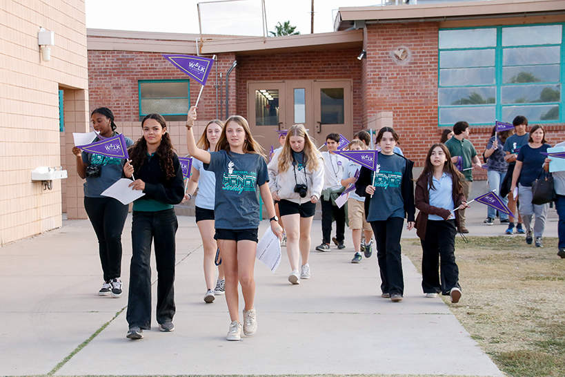 Students walk around campus holding up their purple Ruby Bridges pennants
